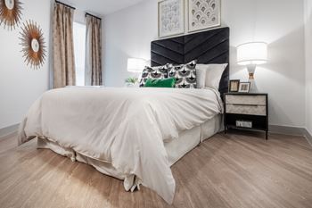 a bedroom with hardwood floors and a large bed with a white comforter